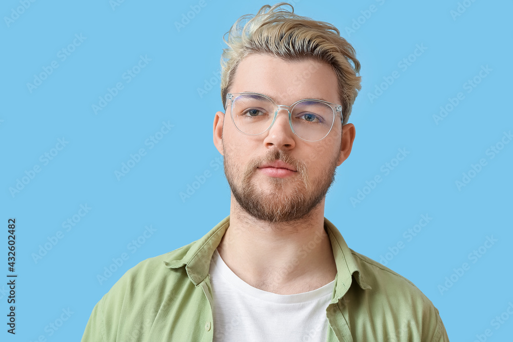 Young man wearing eyeglasses on color background