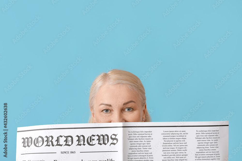 Mature woman with newspaper on color background