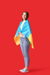 Wall Mural - Beautiful young woman with Ukrainian flag on color background