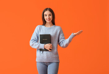 Canvas Print - Young woman with Bible on color background
