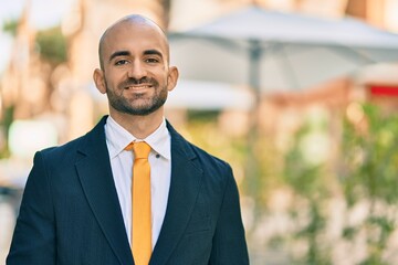 Young hispanic bald businessman smiling happy standing at the city.