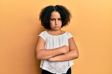 Sticker - Young little girl with afro hair wearing casual clothes skeptic and nervous, disapproving expression on face with crossed arms. negative person.