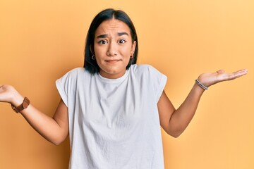 Sticker - Young asian woman wearing casual white t shirt clueless and confused with open arms, no idea and doubtful face.