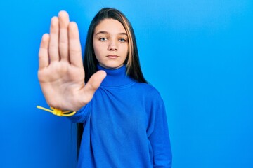 Sticker - Young brunette girl wearing turtleneck sweater doing stop sing with palm of the hand. warning expression with negative and serious gesture on the face.