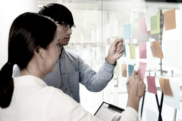 Poster - businessman and woman are standing in a consultation with a plan using sticky paper