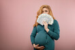 Serious pregnant woman in a green dress counts money