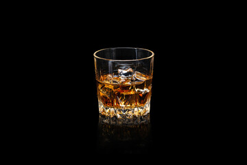 Wall Mural - Glass of whiskey with ice cubes on a dark reflective surface isolated on black.