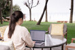 © uv_group - Young woman using laptop outdoor in summer. Distant work, working online concept