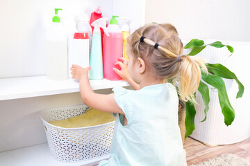 Wall Mural - Toddler touches bottles of household chemicals, household cleaning products.