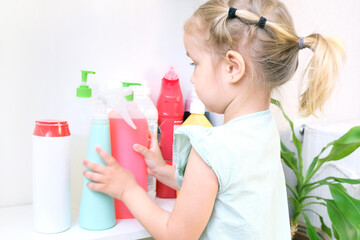 Wall Mural - Toddler touches bottles of household chemicals, household cleaning products.