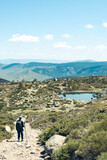 Fototapeta Na drzwi - an unrecognizable person walking towards a small lake on top of a mountain.