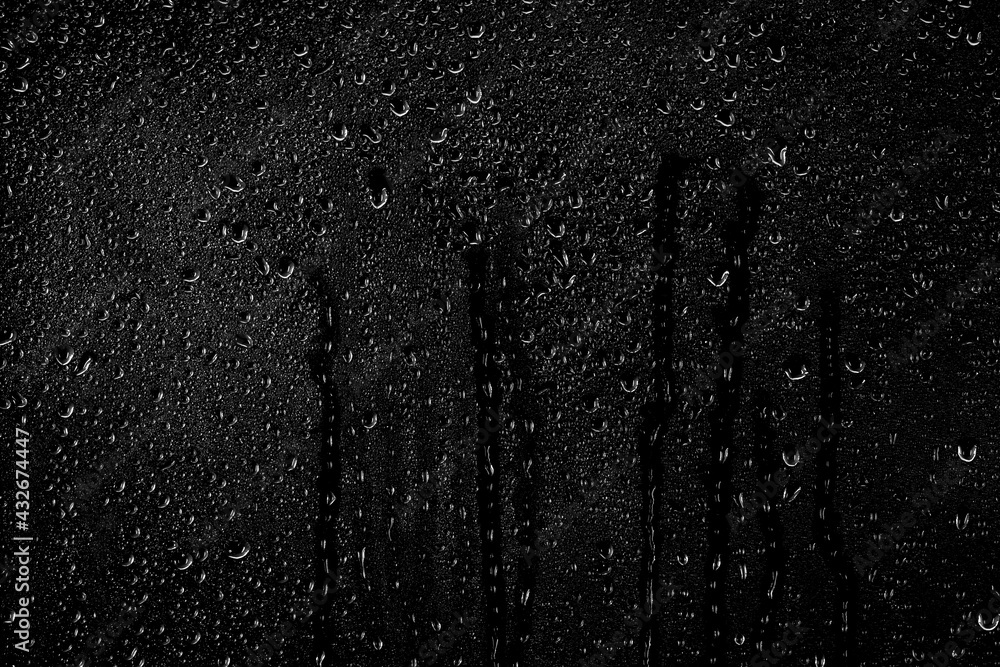 Drops of water flow down the surface of the clear glass on a black background. Texture for creativity. - obrazy, fototapety, plakaty 