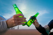 © magui RF - close up. Two friends toast with beer bottles on a sunny day