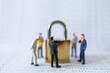© Montri Thipsorn - Business and Security Concept. Group of businessman miniature figure people standing around gold master key lock on bank passbook.