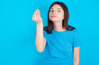 © Jihan - young beautiful Caucasian woman wearing blue T-shirt over blue wall Doing Italian gesture with hand and fingers confident expression