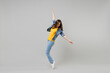 Full length side view young caucasian woman in casual denim jacket yellow t-shirt looking aside leaning back stand on toes dancing isolated on grey background studio portrait People lifestyle concept.