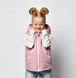 seasonal children's fashion. cozy and comfortable. a teenage girl in a puffy pink sleeveless jacket slips and smiles. take care of yourself in cold weather. happy child in warm clothes.