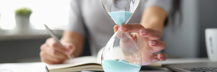 Business woman putting hourglass on digital tablet closeup