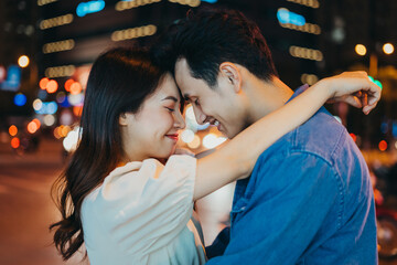 Canvas Print - Young Asian couple embracing together on the street at night