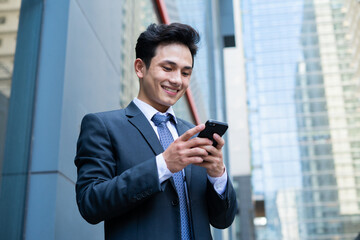 Young Asian businessman using smartphone to text message