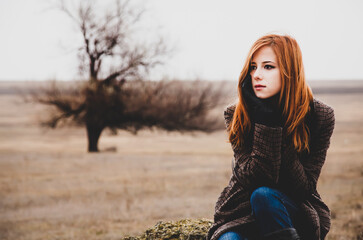 Wall Mural - Redhead girl sitting at outdoor in autumn time.