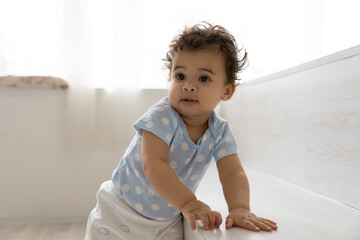 Wall Mural - cute small african american baby girl child stand learn walking alone in cozy home. little biracial 