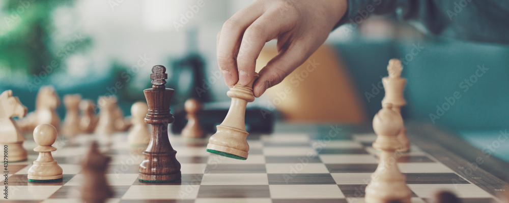 Boy playing chess and moving a piece - obrazy, fototapety, plakaty 