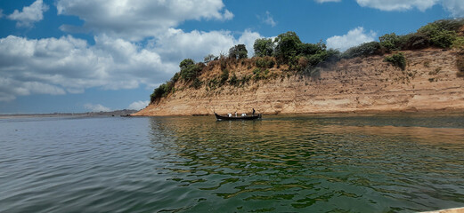 Poster - Beautiful scenery of boat near a rocky cliff under a cloudy sky