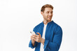 Image of handsome caucasian man using smartphone, holding mobile phone in hands and turn head right, looking at logo banner with company advertisement, standing over white background