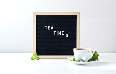 Wall Mural - Tea time. Black letter board with text on table with glass cup of tea with mint leaves