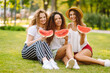 © maxbelchenko - Three young woman relaxing on the grass and eating watermelon.  People, lifestyle, travel, nature and vacations concept.