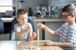 © puhimec - Little boys play a board game with a wooden turret at home.