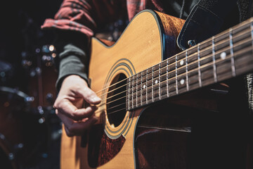 Wall Mural - Guitarist playing acoustic guitar in the dark close up.