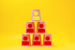 Pyramid of paper cups with the image of the symbols of the little man. Yellow background. The concept of business management, development and career