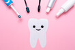 Concept of hygiene of the oral cavity. An electric toothbrush and plastic toothbrushes, with toothpaste and mouth freshener. Smiling tooth cut out of felt. Flat lay. Pink background