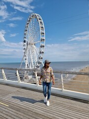Wall Mural -  The Ferris Wheel The Pier at Scheveningen, The Hague, The Netherlands on a Spring day, young woman on the beach