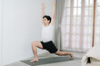 © Gengwit - Asian young man doing yoga at home