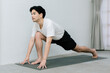 © Gengwit - Asian young man doing yoga at home