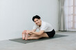 © Gengwit - Asian young man doing yoga at home