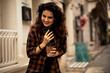 © JustLife - Young smiling woman enjoying outdoors. Beautiful woman drinking coffee while walking in the morning