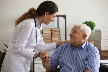 Thank you doctor. Smiling thankful mature sick man holding young female medic nurse hand appreciating for help support care. Happy woman gp greeting old man patient with recovery good analyses results