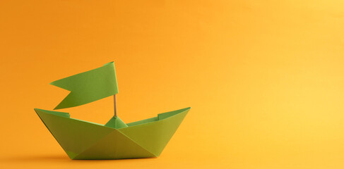 Wall Mural - Green paper boat on a yellow background with space for your text
