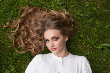 Wall Mural - lovely blonde woman with long healthy hair lying on green grass outdoors