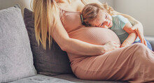 Little Baby Girl Relaxing On Mom's Pregnant Belly - Pregnant Mother With A Toddler - Family Concept