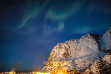 Wall Mural - Aurora borealis over snow mountain in Reine town at Lofoten Islands