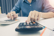 © weerachai - Close up man hand using calculator and writing make note with calculate about cost at sale office.