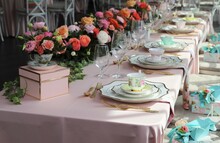 Table Set Up For Bridal Shower On Bright Summer Day With Flowers And Vintage Tea Cups On Each Plate