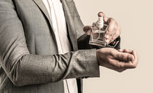 Men Perfume In The Hand On Suit Background. Man In Formal Suit, Bottle Of Perfume, Closeup. Fragrance Smell. Men Perfumes. Fashion Cologne Bottle