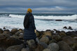 © Евгений Вершинин - Portrait from back of warmly dressed woman in defocus standing in front of sea looking far away looking at winter rough water in slow motion.