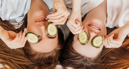 Wall Mural - two girls make homemade face and hair beauty masks. cucumbers for the freshness of the skin around t
